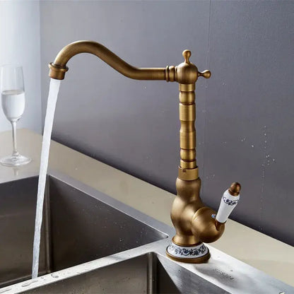 Decorbites antique brass basin faucet with ornate detailing and white ceramic handle featuring blue floral patterns