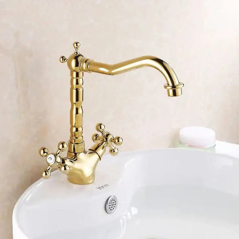 Gold-colored decorbites antique brass basin faucet with ornate cross handles and a swivel curved spout