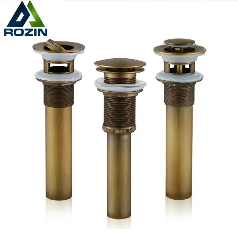 Three bronze-finished antique brass basin sink drains with white ceramic stoppers and textured metallic bodies