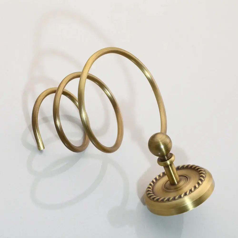 Antique brass bathroom hardware set featuring a brass curtain ring with spiral design and rope-edged base by DecorBites