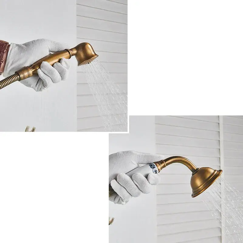 Antique brass freestanding bathtub filler with handheld showerhead featuring curved spout and blue floral handle detailing
