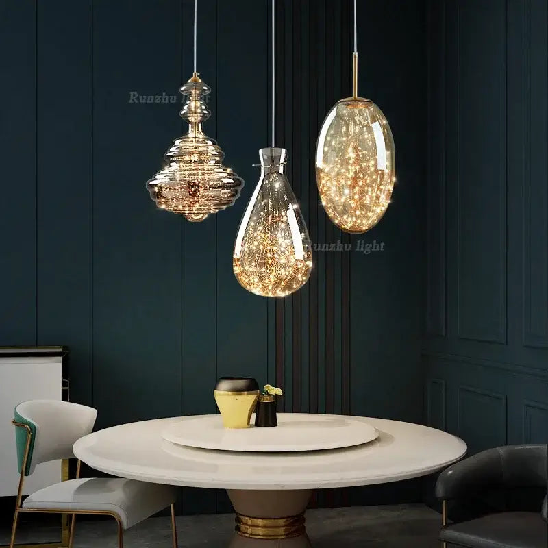 Three elegant antique brass glass pendant lights with warm fairy lights hang above a dining table in a brass glass chandelier