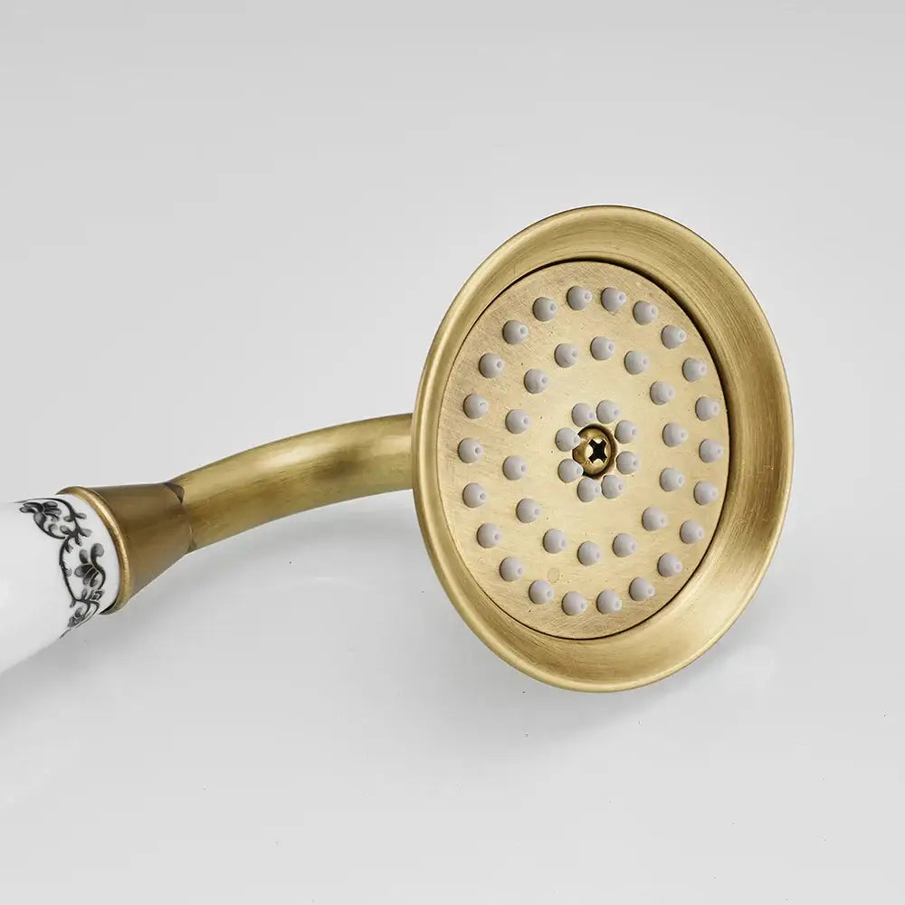 DecorBites™ antique brass hand held shower with a decorative white ceramic handle featuring black floral patterns and multiple nozzles