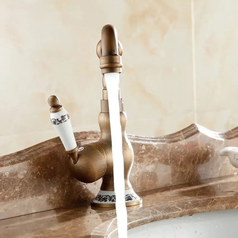 DecorBites antique brass single handle basin faucet with white ceramic handle and black floral patterns on base