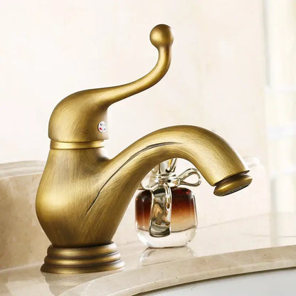 Decorbites antique brass single handle deck mount bathroom sink faucet with curved spout and ornate handle in brass finish