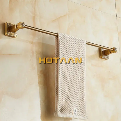 Antique brass single towel bar by DecorBites with ornate square brackets holding a beige textured towel wall mounted
