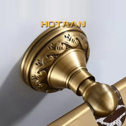 Antique brass toilet paper holder with ornate scrollwork and polished cylindrical handle for wall mounted bathroom use
