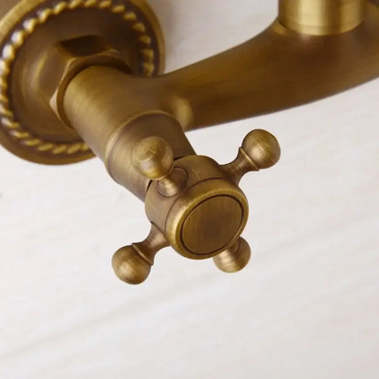 Decorbites antique brass wall mounted shower faucet with antique brass cross-handle and ornate rope detailing on base