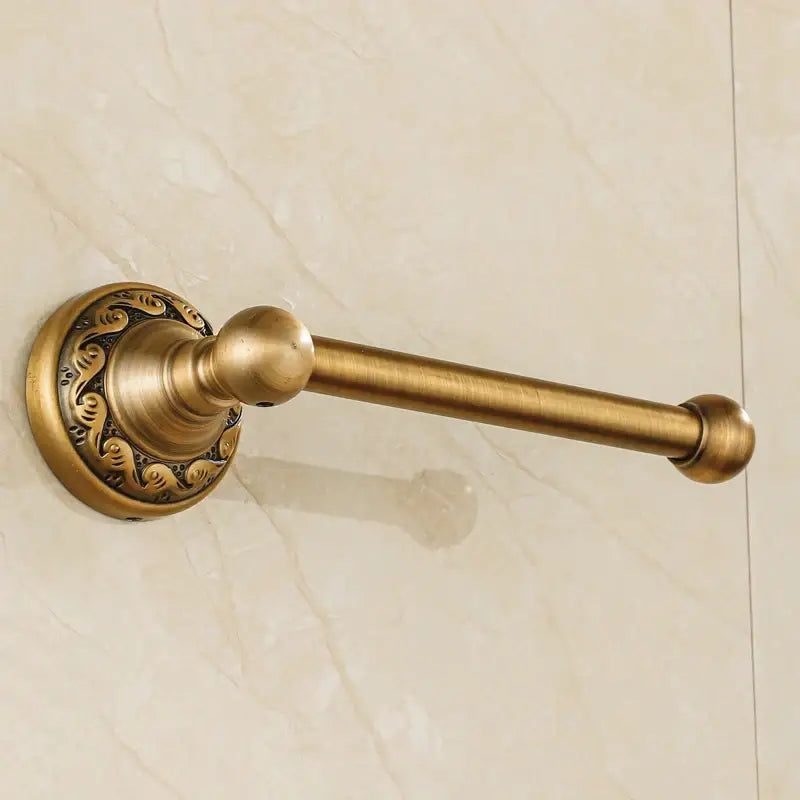 DecorBites™ antique brass toilet paper holder with ornate scrollwork and spherical end caps for vintage bathroom use