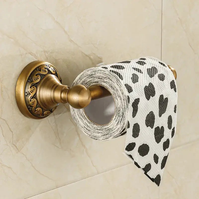 DecorBites™ antique brass toilet paper holder with ornate scrollwork holding white tissue paper with black heart leopard print
