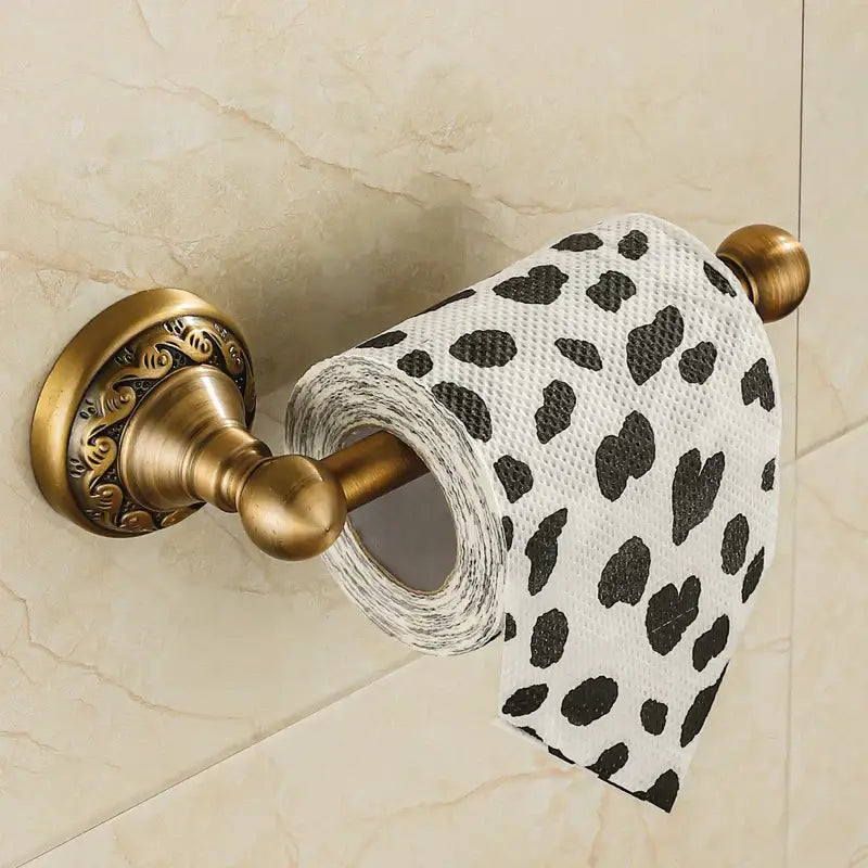 DecorBites antique brass wall mounted toilet paper holder with ornate detailing holding white roll with black hearts