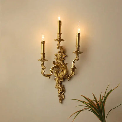 DecorBites™ antique brass wall sconce with three candle-style lights and intricate baroque detailing for elegant lighting