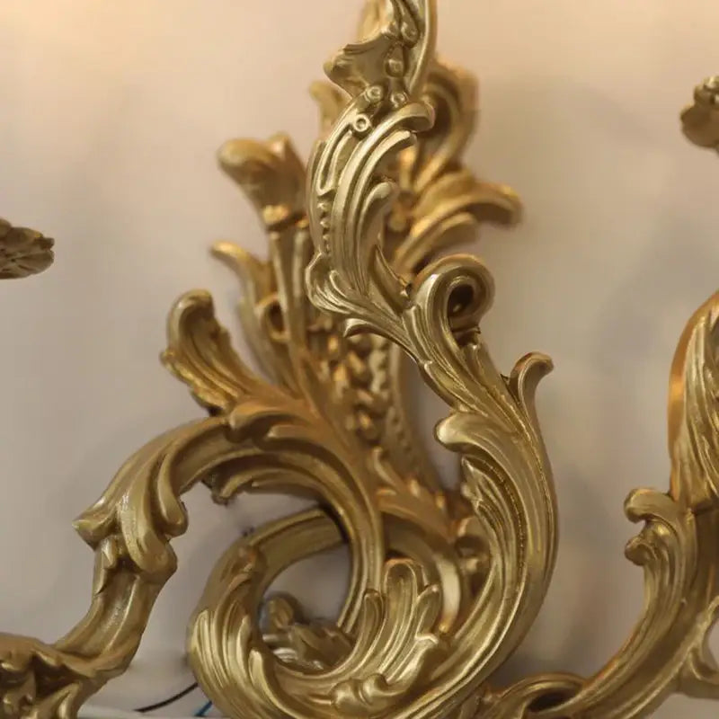DecorBites™ antique brass wall sconce with golden ornate baroque-style scrollwork for vintage royal lighting