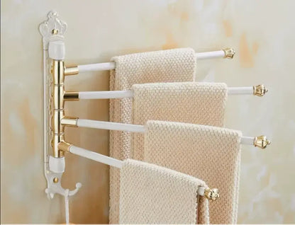 Gold and white ornate antique carved swivel towel rack with four arms holding cream textured towels for bathroom use