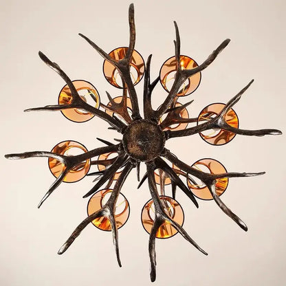 DecorBites antler chandelier with dark textured metal arms and amber glass shades for modern rustic living rooms