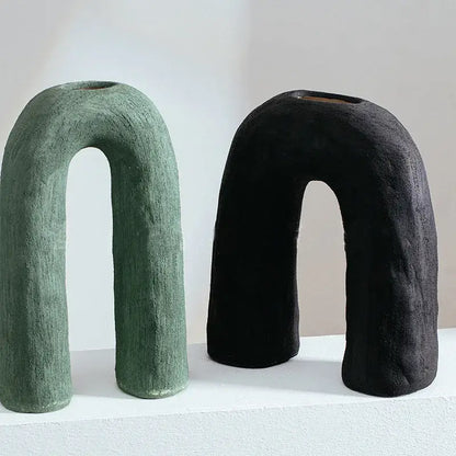 Two decorbites arc ceramic vases in muted green and black with textured matte finish and u-shaped geometric design