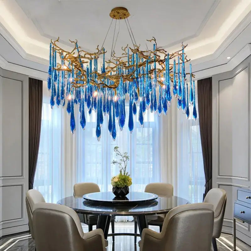 DecorBites Art Deco blue queen crystal chandelier with golden branching arms hangs above dining table