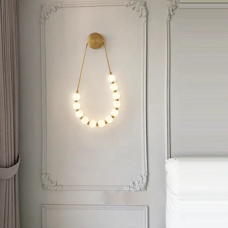 Gold-toned decorbites™ art deco led wall sconce with glowing spherical bulbs in elegant curved black gold design