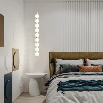 Modern pendant light with seven glowing white glass bulbs on a gold-toned decorbites art deco led fixture