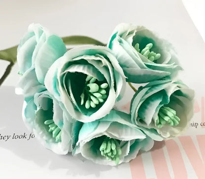 A cluster of delicate light teal and white decorbites artificial peony tea silk flowers with green centers for weddings
