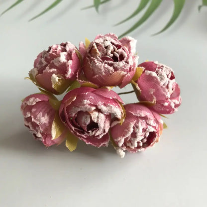 A cluster of five pink decorbites artificial roses with textured fabric petals and yellow-green stems for bridal décor