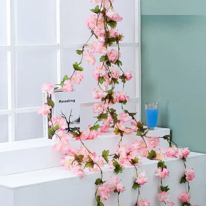 A delicate pink decorbites artificial sakura vine with green leaves and slender stems for wedding garden decoration