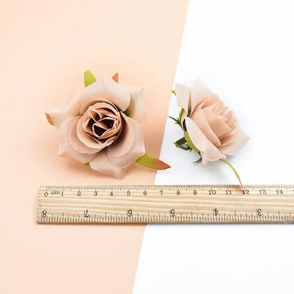Two delicate blush pink decorbites artificial silk roses with green stems displayed beside a wooden ruler for scale