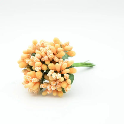 A delicate cluster of decorbites artificial stamen flowers in orange and cream with green fabric leaves for home decor