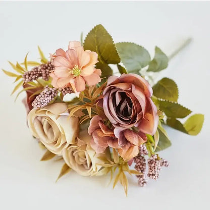 A delicate decorbites artificial western rose bouquet in soft peach mauve cream with green leaves and purple berries for wedding decor