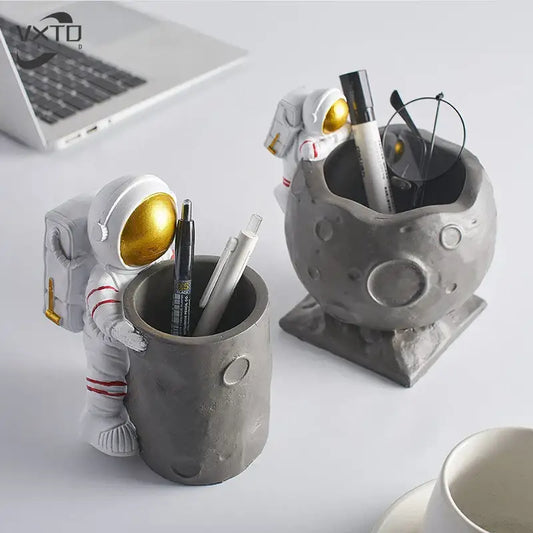 White astronaut figurine with gold visor and red-striped suit holding gray cratered moon pen holder figurines for desk decor