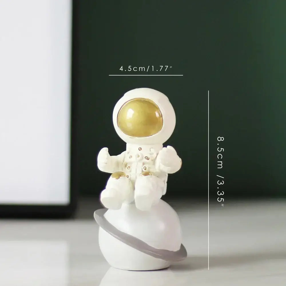 Decorbites astronaut figurine abstract sculpture in white with gold visor and silver details on a white planet with gray ring