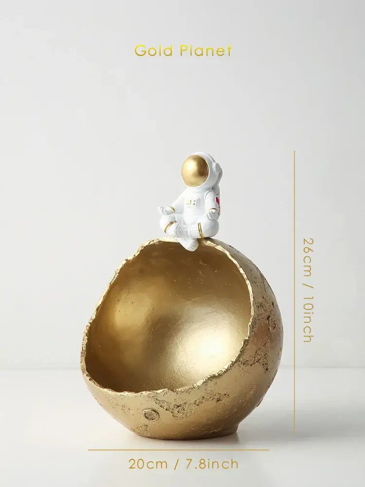 Gold planet-shaped decorative bowl with white astronaut figurine on top decorbites astronaut figurine abstract sculpture