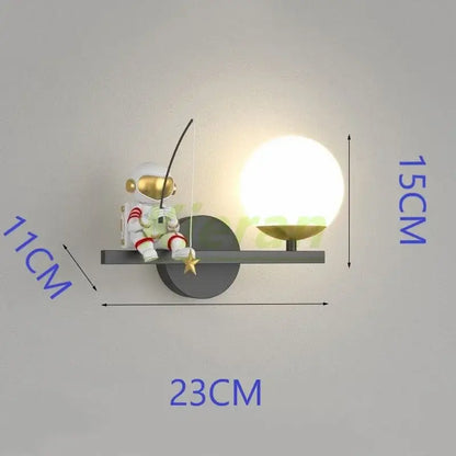 Cute white DecorBites astronaut LED wall lamp with gold accents seated on black metal shelf beside glowing sphere lamp