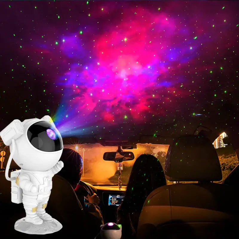 White decorbites astronaut projector starry night light casting vibrant pink purple and green stars on car ceiling