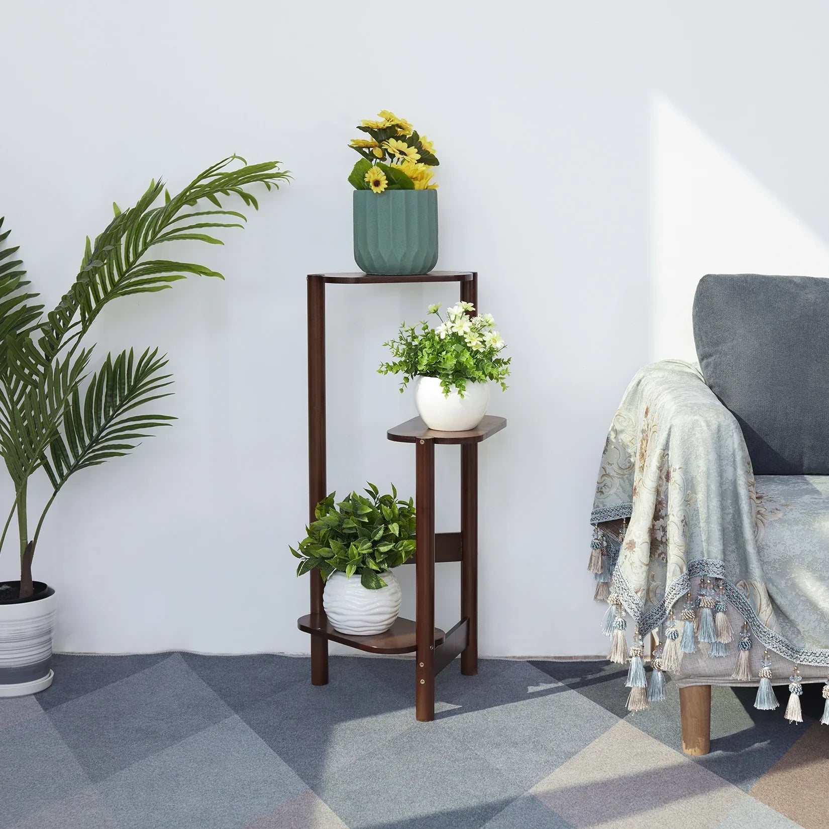 Dark brown wooden bamboo tall corner plant stand with three tiers and angled legs holding various potted plants