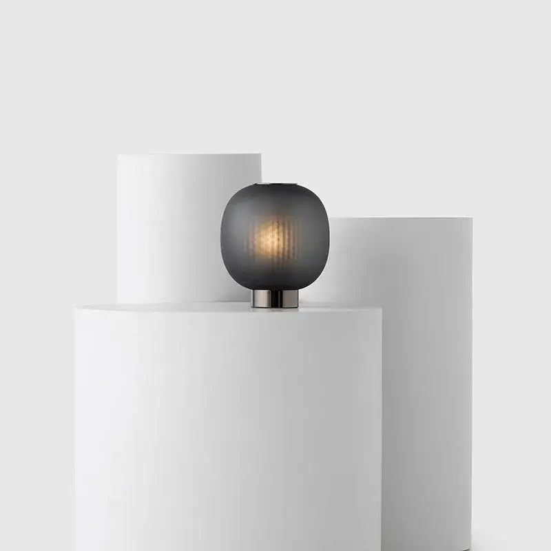 A decorbites black glass ball table light with a sleek dark gray frosted glass shade and metallic base for bedroom use