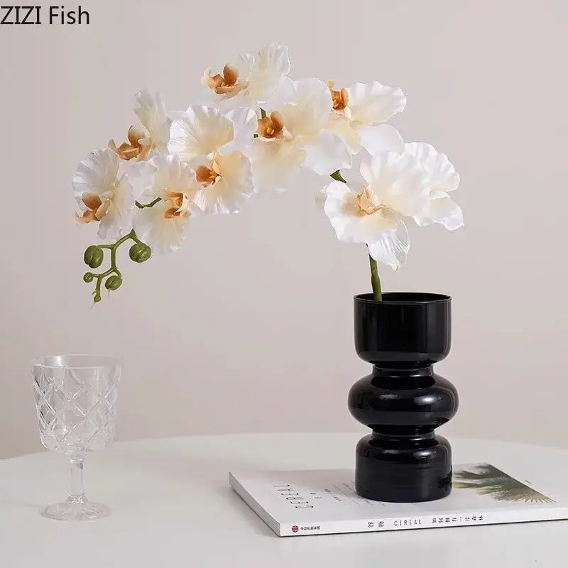 Decorbites black glass vase with black ceramic stacked segments holding white artificial flowers for minimalist decor