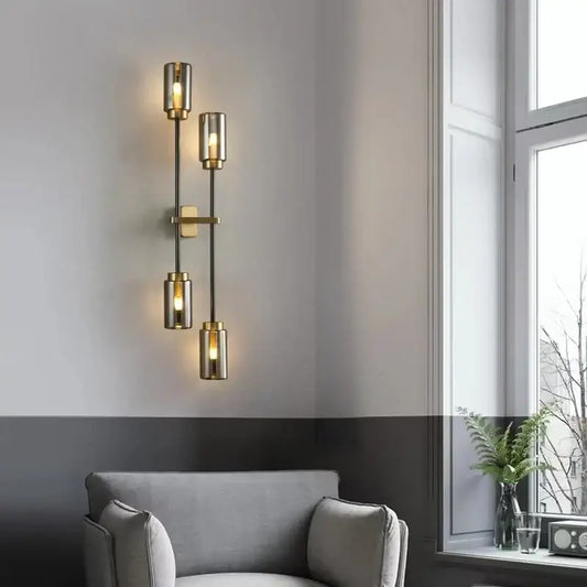 Modern brass-finished decorbites black glass wall lamp with four cylindrical shades emitting warm light for living room decor