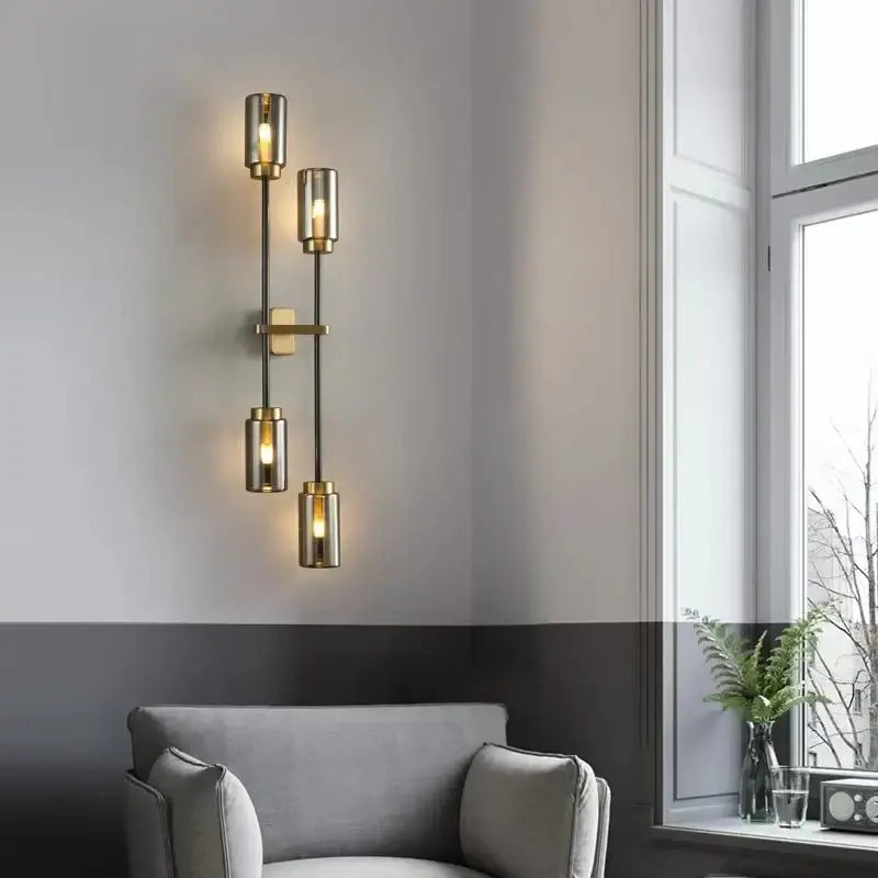 Modern brass-finished decorbites black glass wall lamp with four cylindrical shades emitting warm light for living room decor