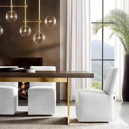 Decorbites black gold brass chandelier with clear glass art above gold-toned dining table with dark wood top and modern legs