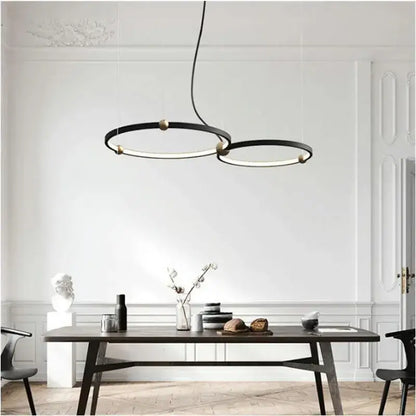 Modern black gold chandelier with metal LED rings hanging above a dining table by DecorBites black gold