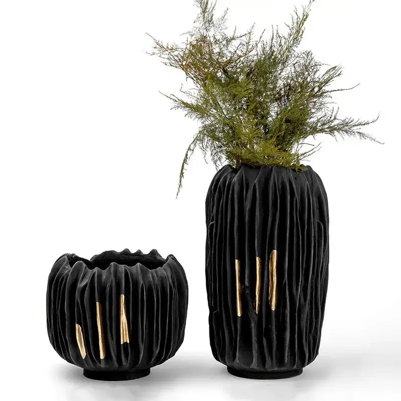 Black ceramic resin vases with gold crease texture and black gold accents, one holding greenery by DecorBites