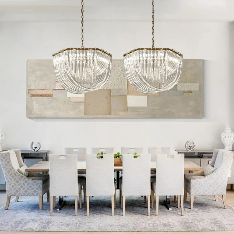 Two elegant clear glass DecorBites black gold crystal pendant lights with gold metal frames hang above a dining table