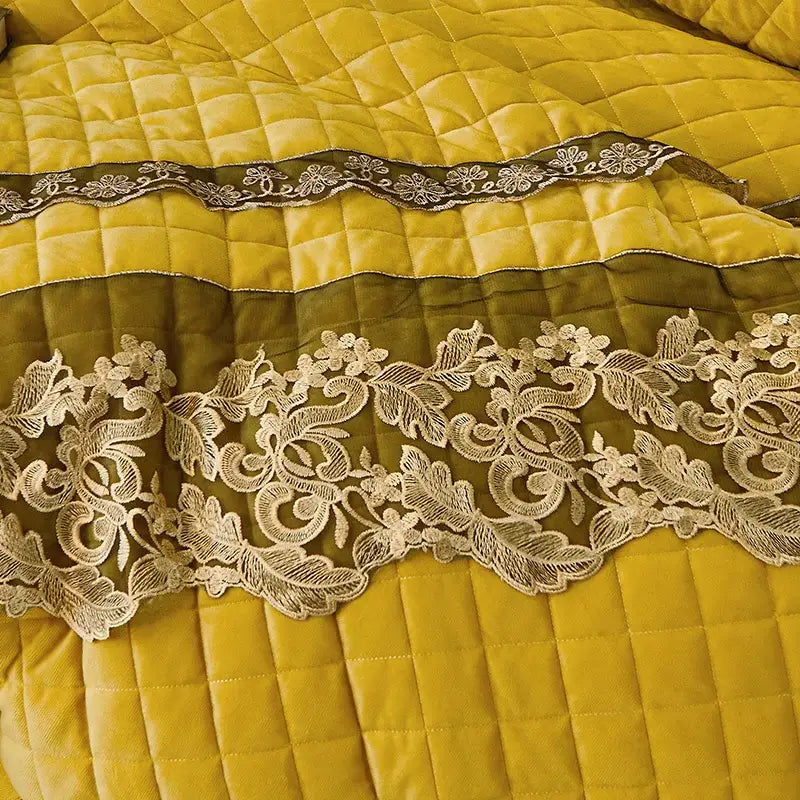 A cream lace trim with floral patterns stitched on quilted mustard yellow fabric in decorbites black gold luxury bedding set