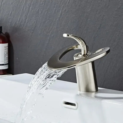 Modern brushed nickel waterfall basin faucet with sleek curved spout and circular base for hot cold mixer tap
