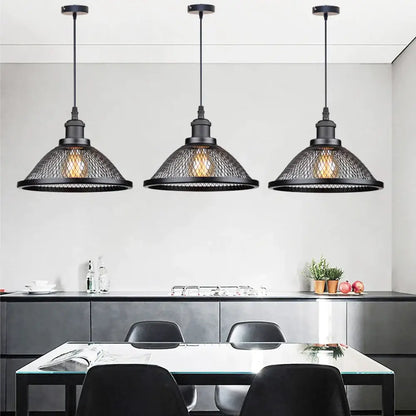 Three black industrial cage pendant lights by DecorBites hang above a dining table for kitchen island lighting