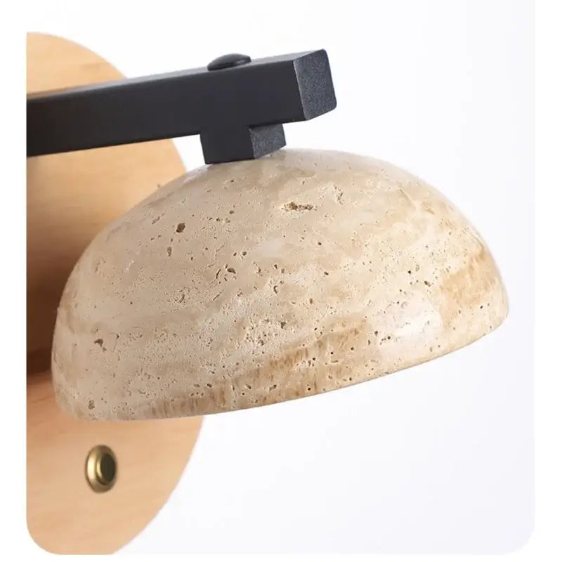 Beige stone dome wall lamp with a black iron led wall light arm for bedside use by DecorBites™