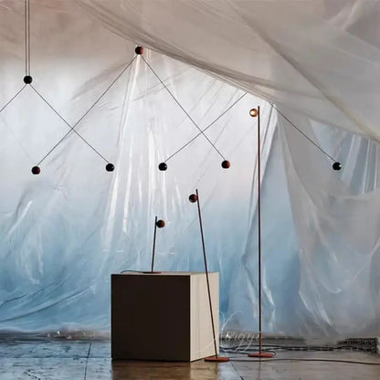 Modern geometric decorbites black led floor lamp with slender black metal frame and spherical red bulbs suspended by wires