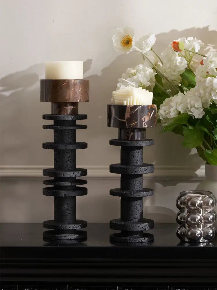 Two elegant decorbites black marble pillar candlesticks with stacked circular tiers holding white pillar candles