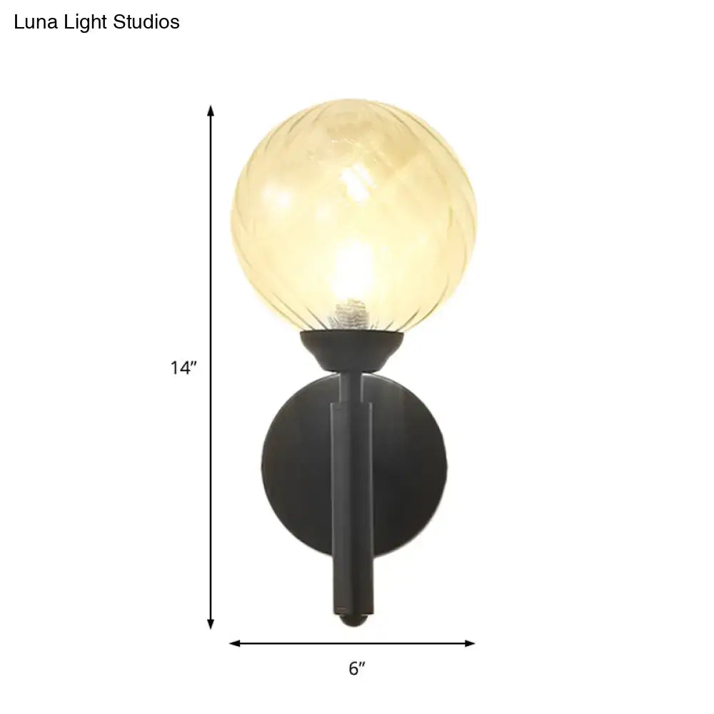 Modern black wall sconce with a warm amber spherical lamp and clear textured glass for bedroom lighting
